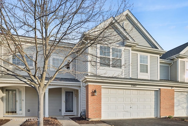 view of property featuring a garage, brick siding, and driveway