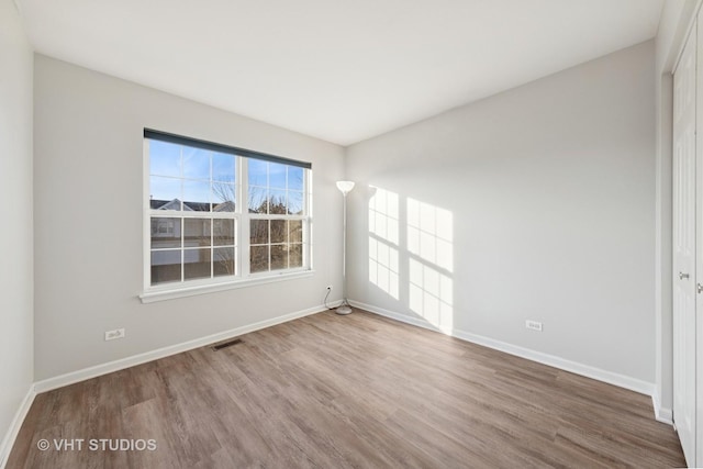 unfurnished room featuring visible vents, baseboards, and wood finished floors