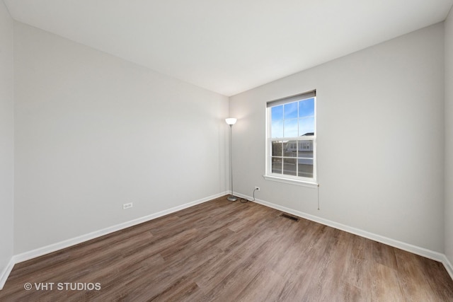 spare room with wood finished floors, baseboards, and visible vents