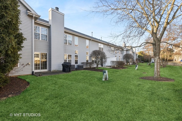 back of house featuring a lawn, central AC, and a chimney