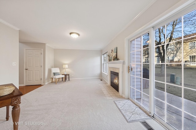 living area featuring visible vents, baseboards, ornamental molding, carpet flooring, and a tile fireplace