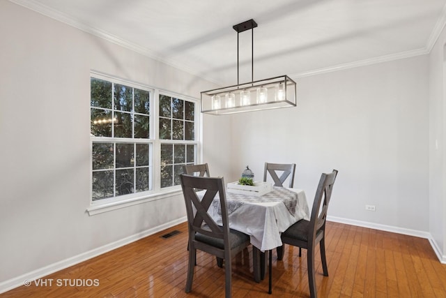 dining room with hardwood / wood-style floors, a healthy amount of sunlight, baseboards, visible vents, and ornamental molding