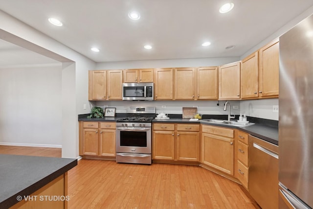 kitchen with recessed lighting, a sink, stainless steel appliances, light wood-style floors, and dark countertops