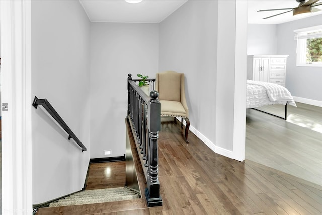 stairway featuring a ceiling fan, baseboards, and wood finished floors