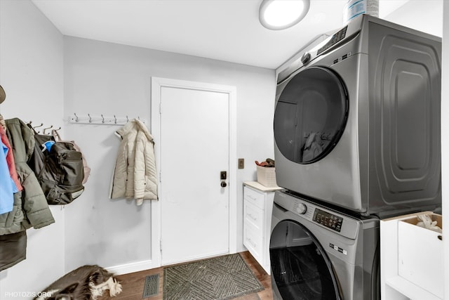 laundry room featuring stacked washer and dryer, visible vents, and wood finished floors