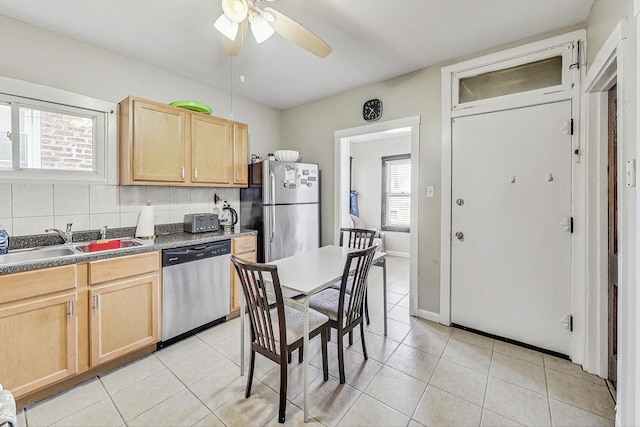 kitchen with light tile patterned floors, stainless steel appliances, decorative backsplash, light brown cabinetry, and a sink