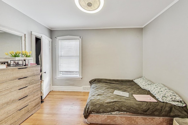 bedroom with visible vents, baseboards, light wood-style flooring, and crown molding