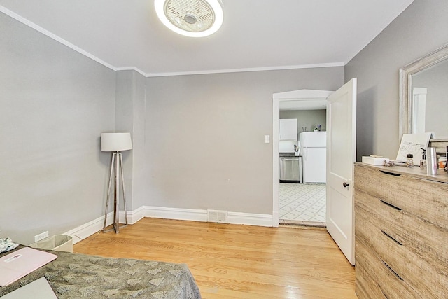 bedroom featuring light wood-type flooring, freestanding refrigerator, crown molding, and baseboards