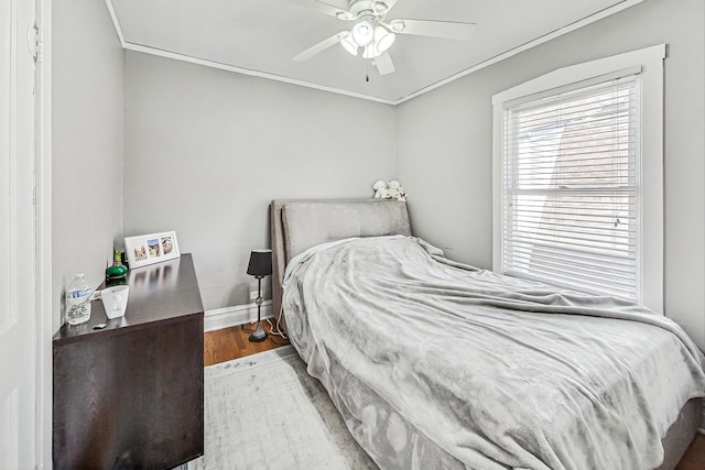 bedroom with ornamental molding, a ceiling fan, baseboards, and wood finished floors