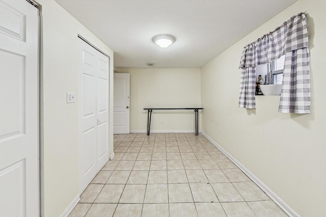 hall featuring light tile patterned floors and baseboards