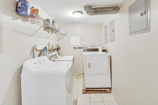 laundry area with washing machine and clothes dryer, light tile patterned floors, a sink, electric panel, and baseboards