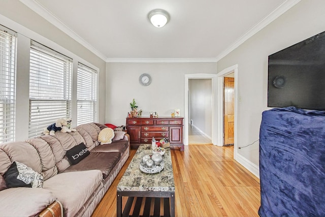 living room featuring baseboards, ornamental molding, and light wood-style floors