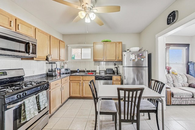 kitchen with light tile patterned floors, appliances with stainless steel finishes, dark countertops, and light brown cabinets