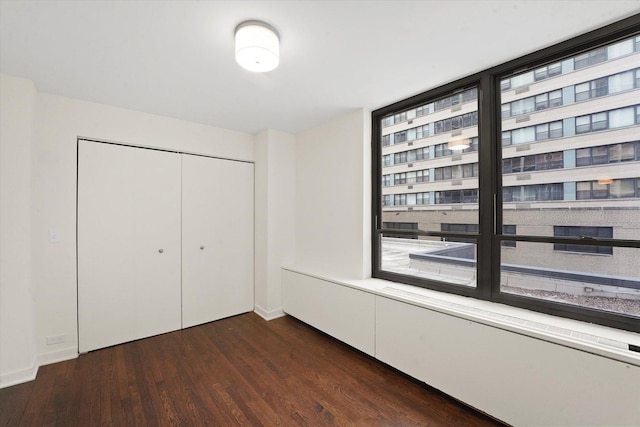 unfurnished bedroom featuring a closet, dark wood finished floors, and baseboards