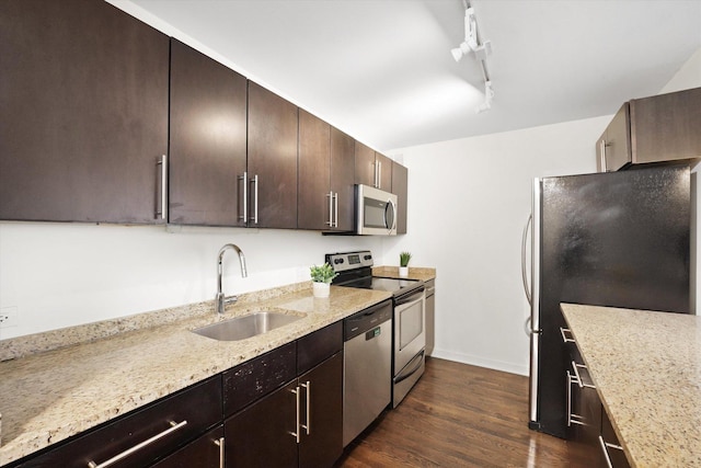 kitchen featuring light stone counters, dark wood-style floors, appliances with stainless steel finishes, a sink, and dark brown cabinets