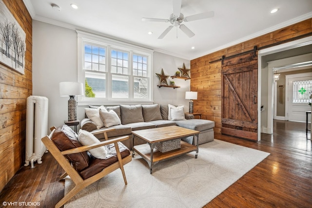 living area featuring radiator heating unit, ornamental molding, wood-type flooring, and a barn door