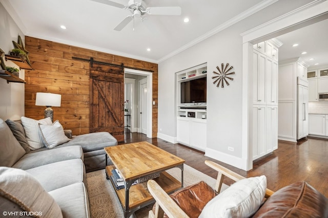 living area with a barn door, dark wood finished floors, a ceiling fan, and crown molding