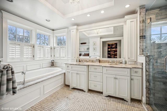 bathroom featuring double vanity, a garden tub, a shower stall, a decorative wall, and a sink