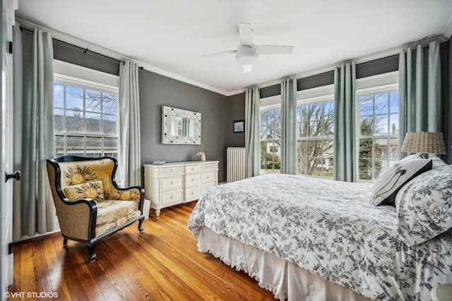 bedroom with crown molding, multiple windows, ceiling fan, and wood finished floors