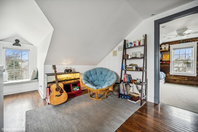 living area featuring lofted ceiling, baseboards, and wood finished floors