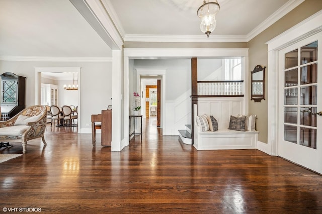 foyer entrance with ornamental molding, stairway, dark wood finished floors, and a notable chandelier