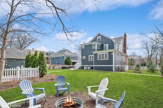 back of property featuring a yard, an outdoor fire pit, fence, and a chimney