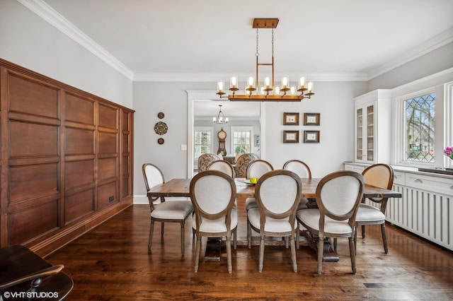 dining space featuring dark wood-style floors, ornamental molding, and a notable chandelier