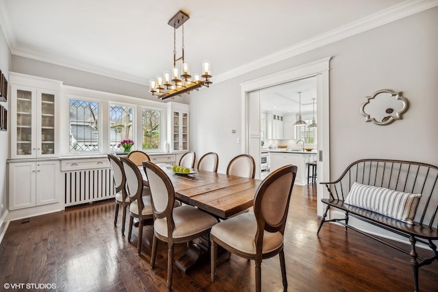 dining space featuring dark wood-style flooring, ornamental molding, radiator heating unit, and a notable chandelier