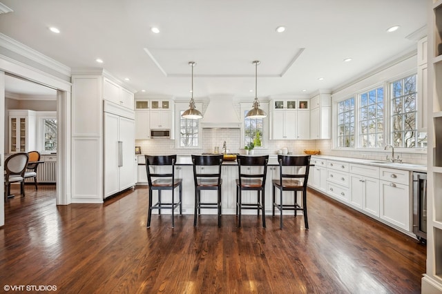 kitchen with glass insert cabinets, a breakfast bar, white cabinets, and built in appliances