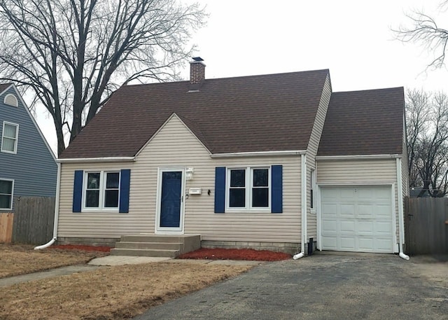 cape cod-style house featuring an attached garage, a chimney, fence, and roof with shingles