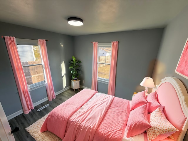 bedroom with dark wood-type flooring, multiple windows, and baseboards