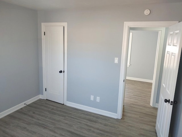 unfurnished bedroom with dark wood-style floors, baseboards, and a closet