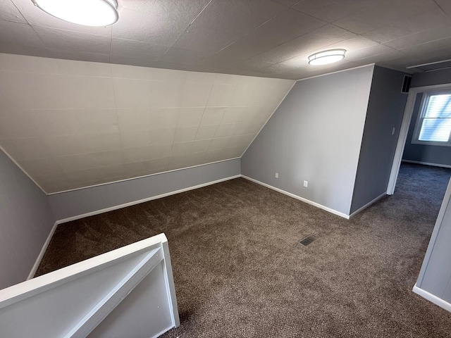 bonus room with lofted ceiling, dark carpet, and baseboards