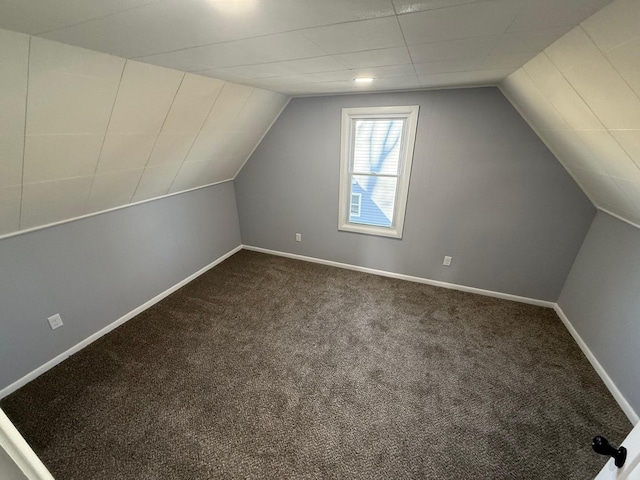 bonus room featuring lofted ceiling, dark colored carpet, and baseboards