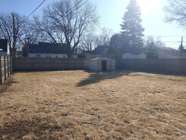 view of yard with an outbuilding, a fenced backyard, and a storage shed