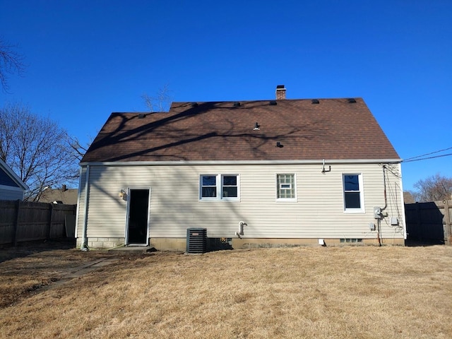 rear view of property featuring a chimney, a shingled roof, a lawn, fence, and cooling unit