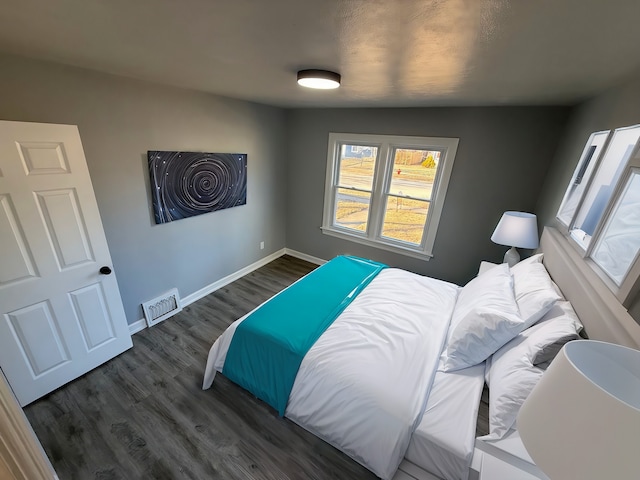 bedroom with wood finished floors, visible vents, and baseboards