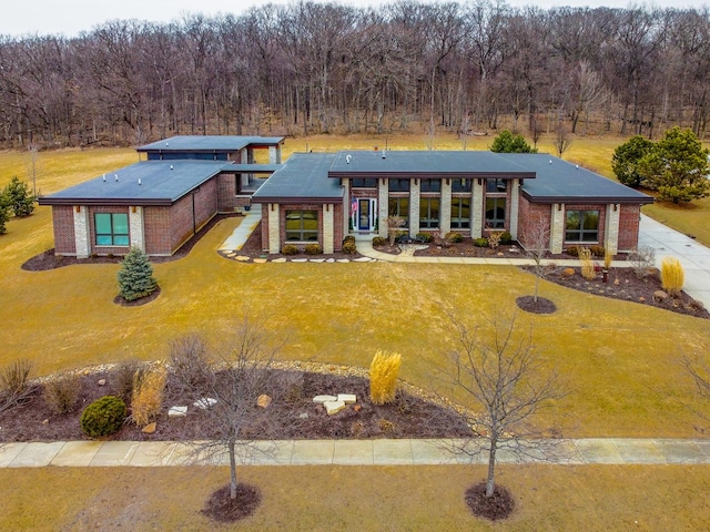 view of front of property with a front lawn, a wooded view, and brick siding