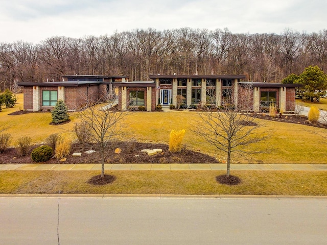 view of front of home featuring a view of trees, brick siding, and a front yard