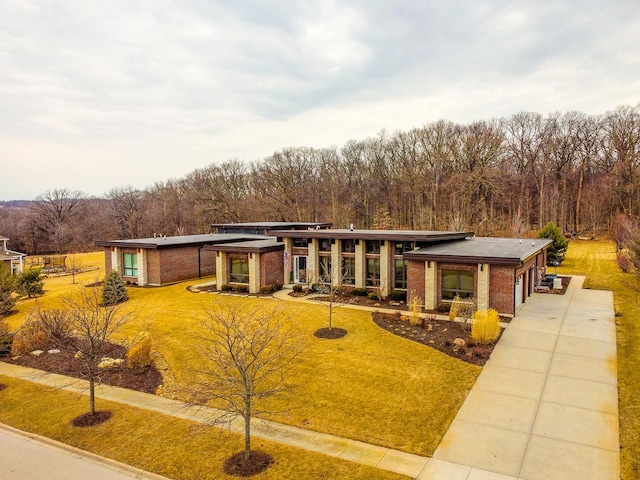 view of front of property featuring brick siding, a garage, driveway, and a front lawn