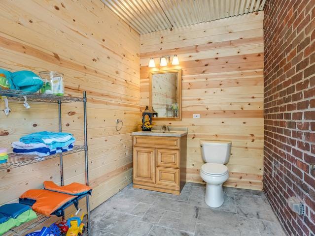 bathroom featuring vanity, wooden walls, and toilet