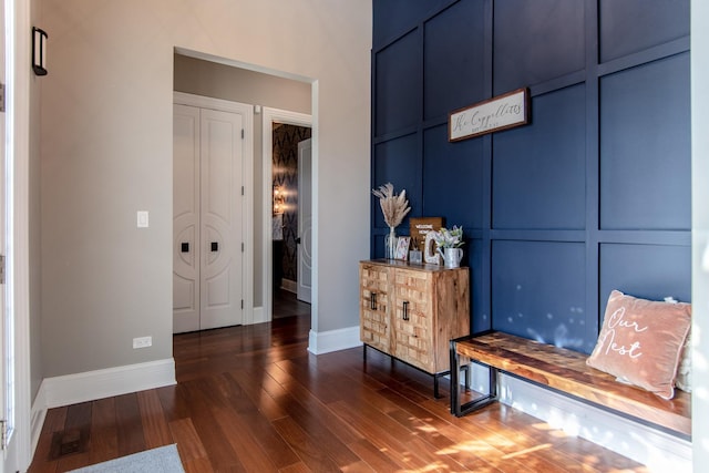 sitting room featuring a decorative wall, wood finished floors, visible vents, and baseboards