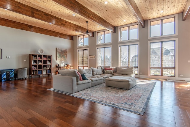 living room with beamed ceiling, a towering ceiling, wood ceiling, and wood-type flooring