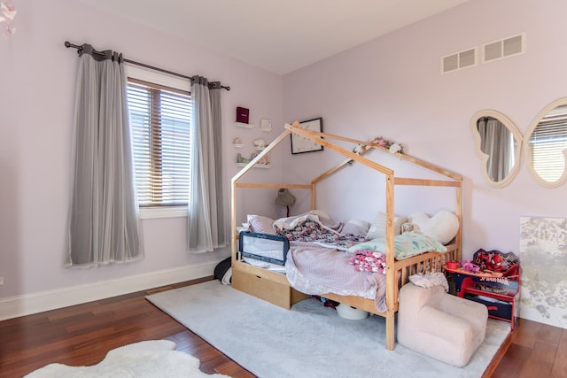 bedroom featuring visible vents, baseboards, and wood finished floors