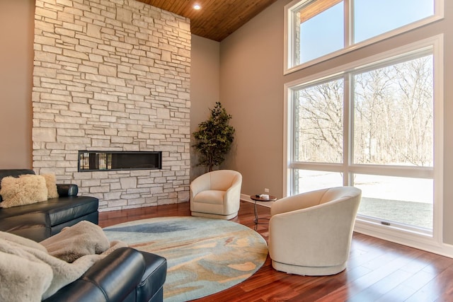 living area with a wealth of natural light, a fireplace, wood ceiling, and wood finished floors