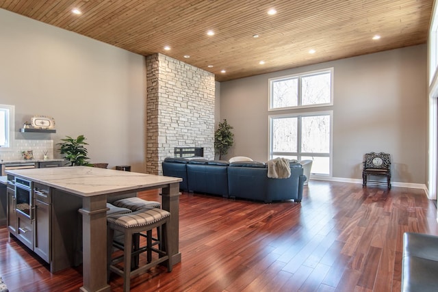 interior space with dark wood finished floors, recessed lighting, a fireplace, baseboards, and wood ceiling