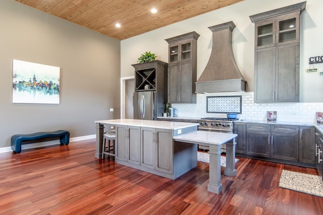 kitchen featuring a kitchen island, a breakfast bar, wood ceiling, custom range hood, and freestanding refrigerator