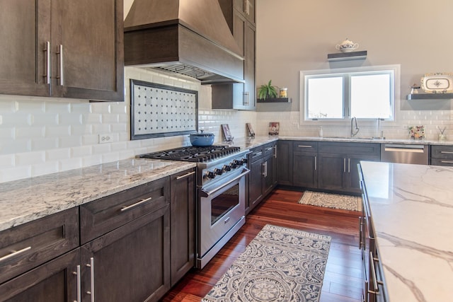 kitchen with custom exhaust hood, dark brown cabinets, appliances with stainless steel finishes, and open shelves