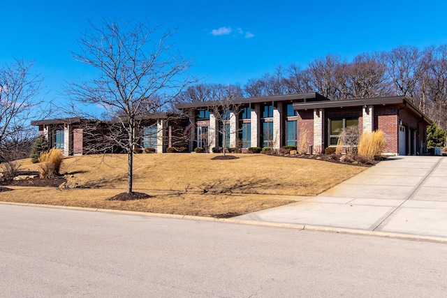 view of front of home featuring brick siding, a garage, concrete driveway, and a front yard