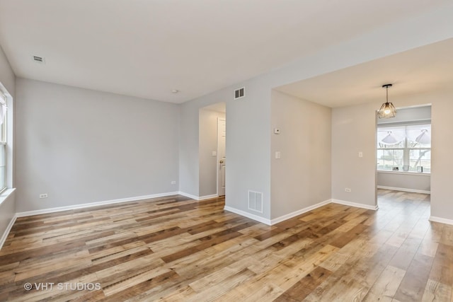 empty room with baseboards, visible vents, and light wood-style floors